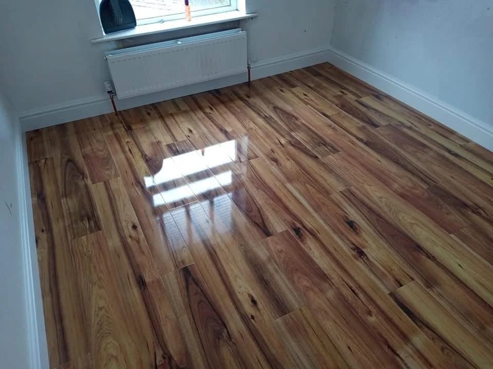 High gloss laminate with strong grain running through an empty bedroom, reflecting the window