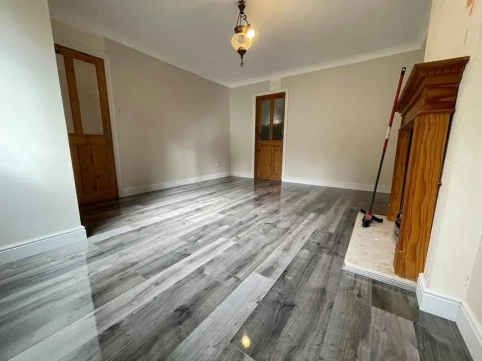 Grey high gloss laminate in an empty room with a fireplace and pine doors