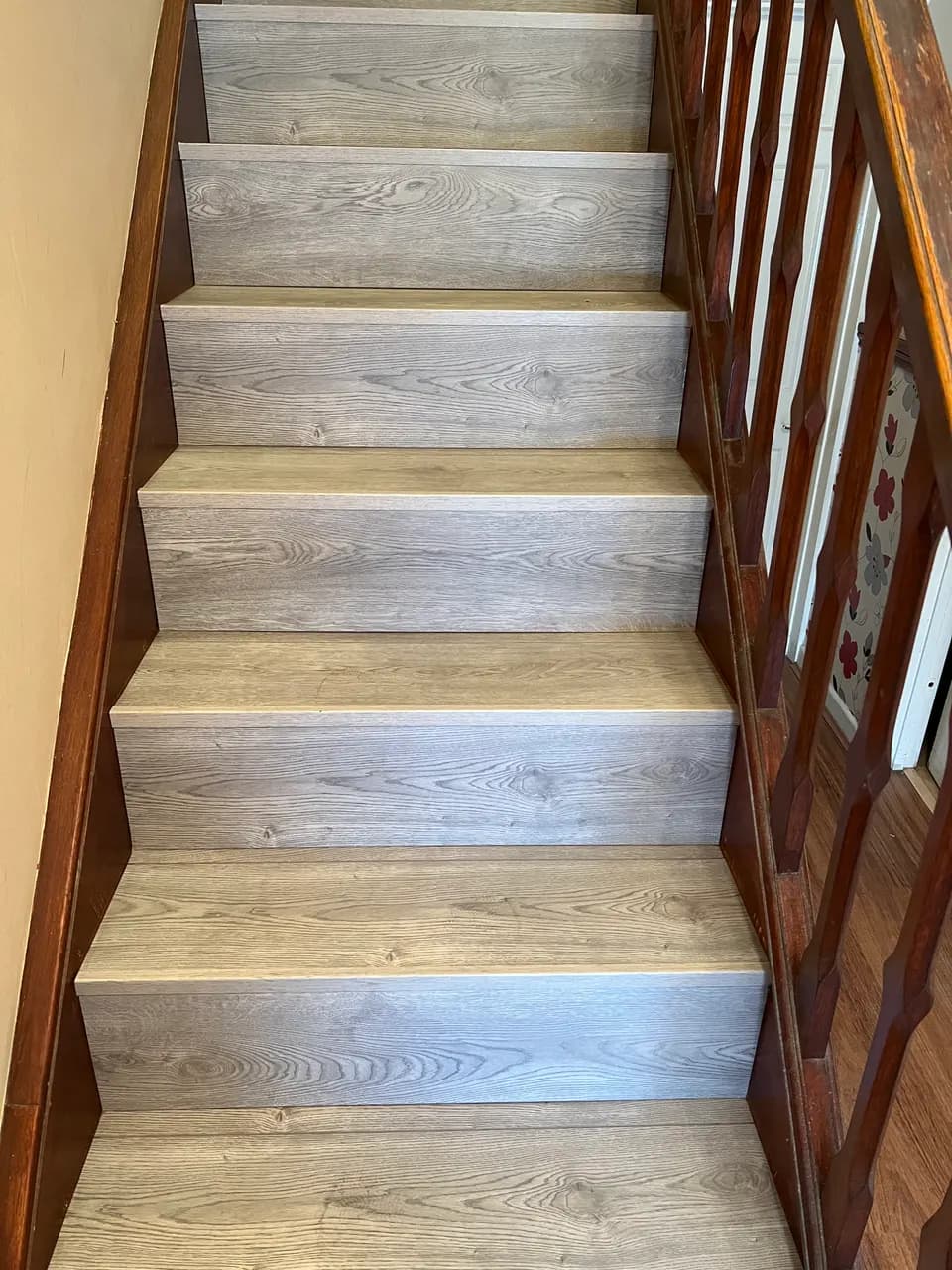 Grey oak laminate treads and risers on a straight staircase with a dark wooden banister