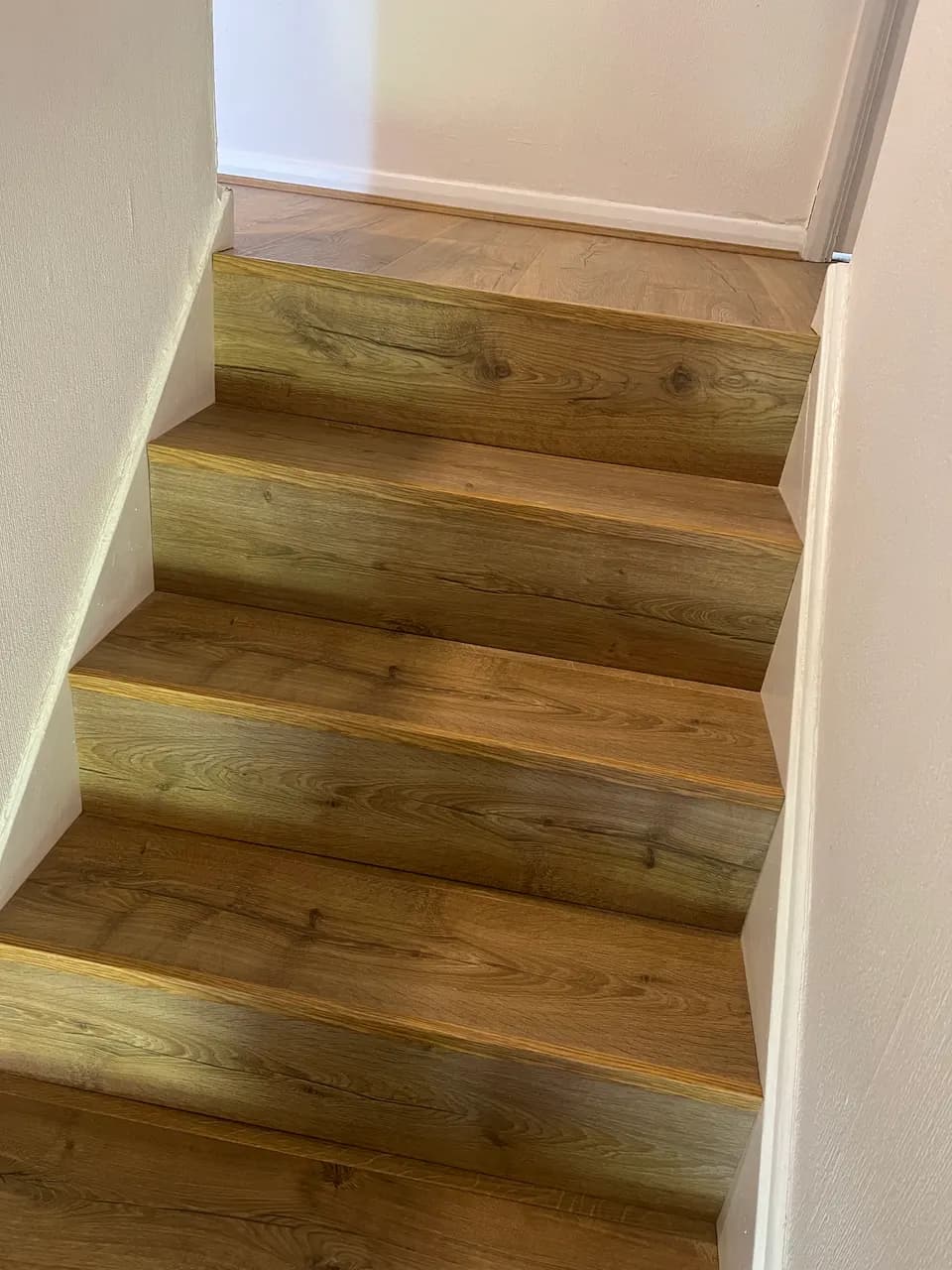 Golden oak laminate stairs leading up to a landing floored in the same board