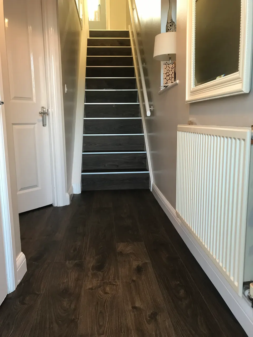 Dark grey laminate hallway floor leading to stairs finished in the same board