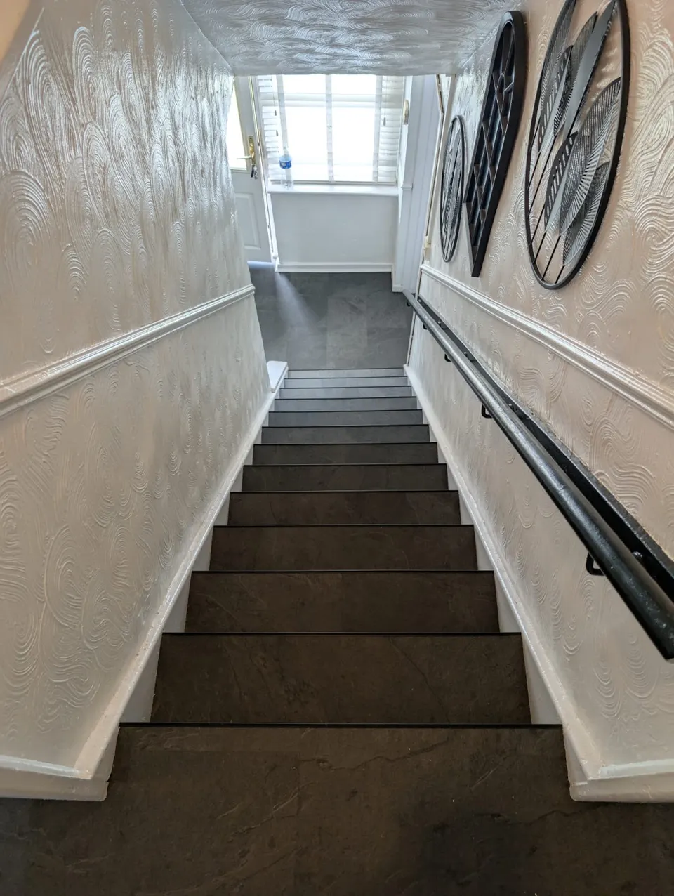 Slate-effect laminate on a straight staircase with a black handrail, looking up to the landing