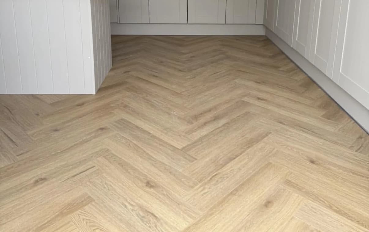 Light oak herringbone click vinyl flooring fitted through a grey shaker kitchen