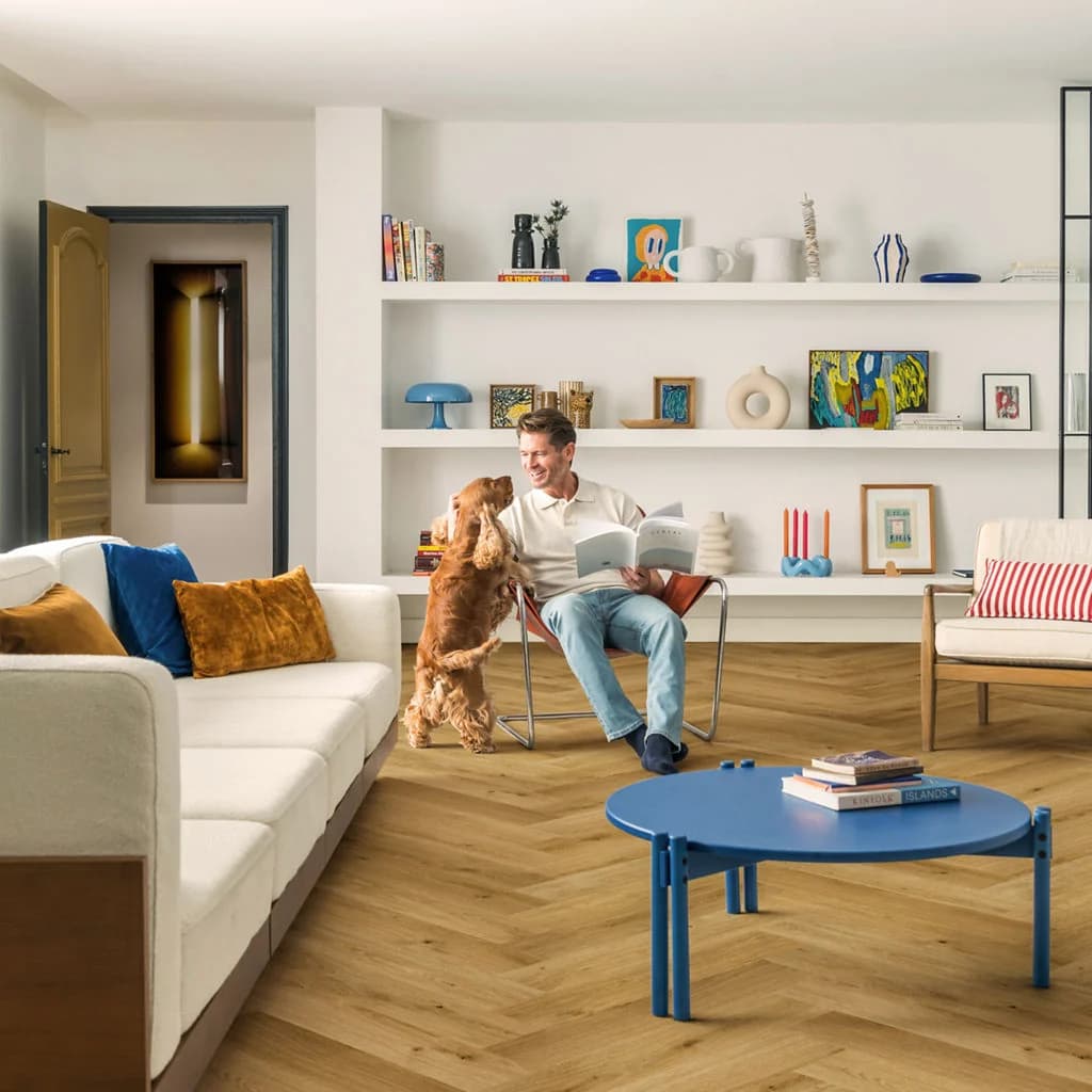 Natural oak herringbone flooring in a bright living room with a man reading and a dog