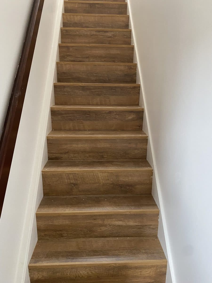 A staircase fitted with oak-effect laminate, tread and riser, with white spindles