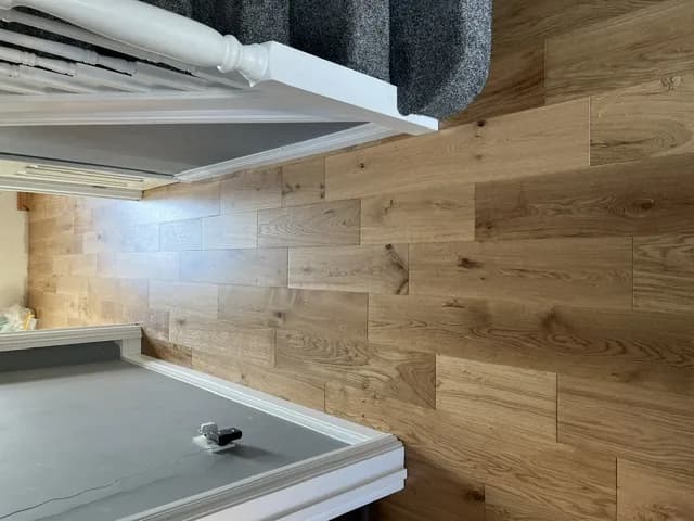 Engineered oak flooring running the length of a hallway past a white spindled staircase