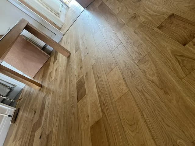 Engineered oak flooring beneath a wooden dining table in a kitchen diner
