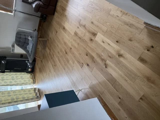 Engineered oak flooring in a living room, running towards patio doors and a reading chair