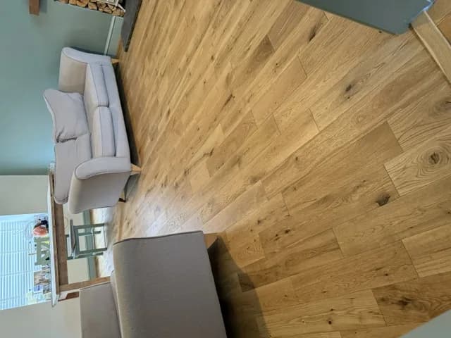 Engineered oak flooring through an open living and dining room with fabric sofas and a log store