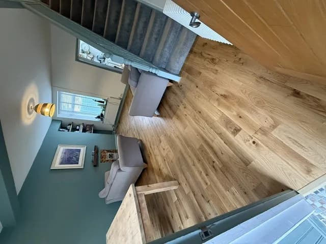 Engineered oak flooring in a teal lounge, running from the dining table through to the foot of the stairs