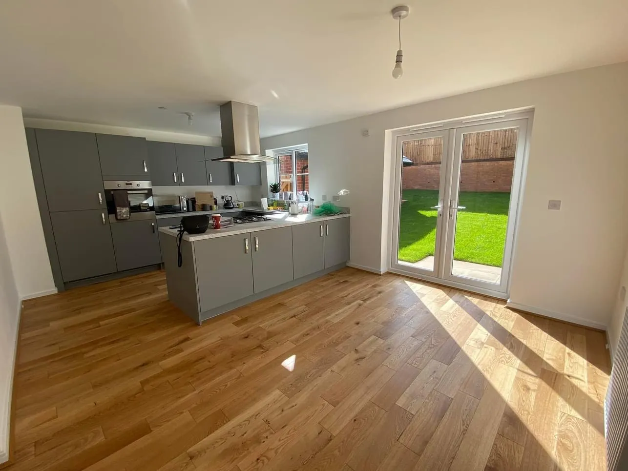 Engineered oak flooring laid through an open-plan kitchen diner, with garden doors at the far end